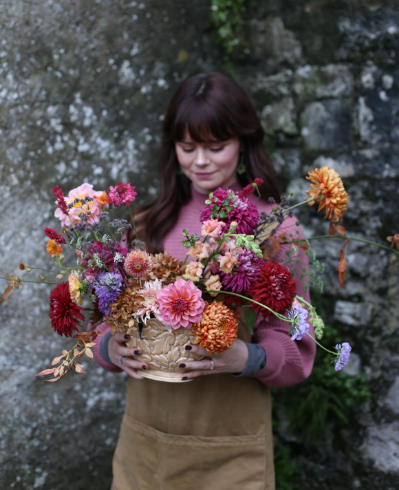 Founder of May & June holding a wild, natural wedding table centrepiece with rich textures, featuring a mix of dried and fresh locally grown British flowers